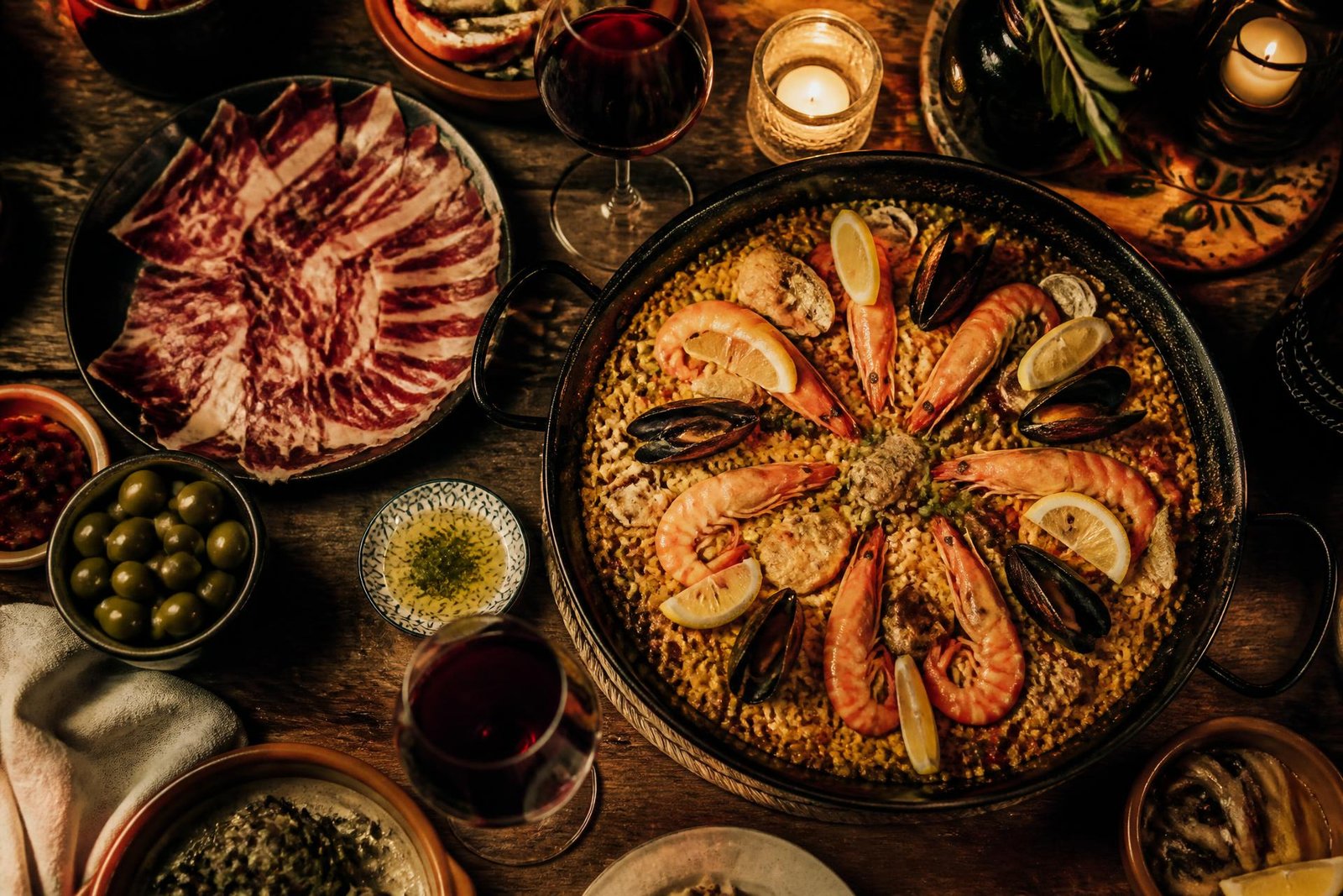 Mesa española con paella de marisco, jamón ibérico, aceitunas y vino tinto